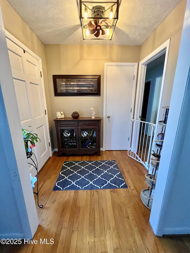 foyer entrance featuring an inviting chandelier, wood finished floors, and a textured ceiling