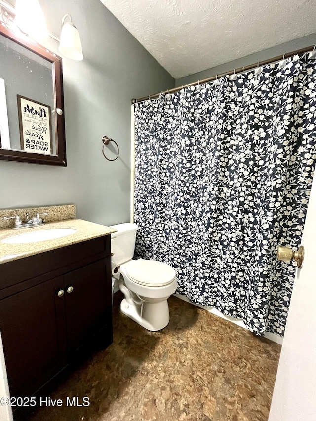 bathroom with vanity, curtained shower, toilet, and a textured ceiling