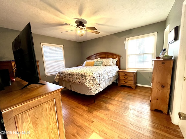 bedroom with light wood finished floors, a textured ceiling, and ceiling fan