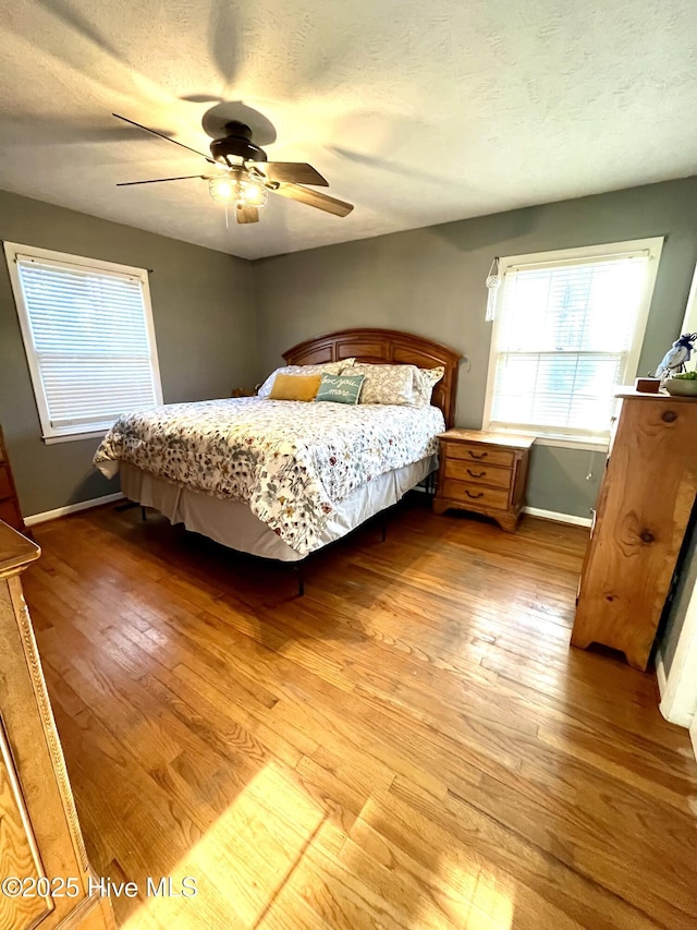 bedroom featuring light wood finished floors, a textured ceiling, and baseboards