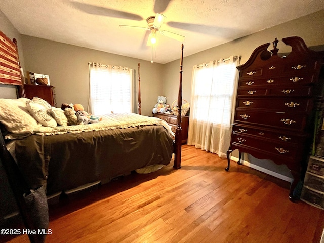 bedroom with multiple windows, light wood-style floors, ceiling fan, and a textured ceiling