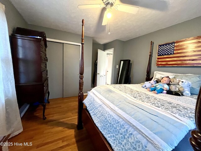 bedroom with a closet, a textured ceiling, wood finished floors, and a ceiling fan