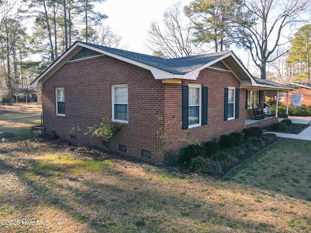 view of home's exterior with crawl space, brick siding, a lawn, and fence