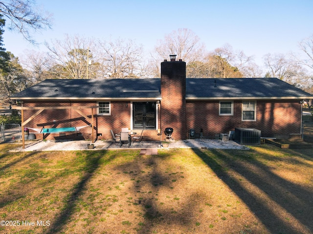 back of house with a patio, a yard, brick siding, and a chimney