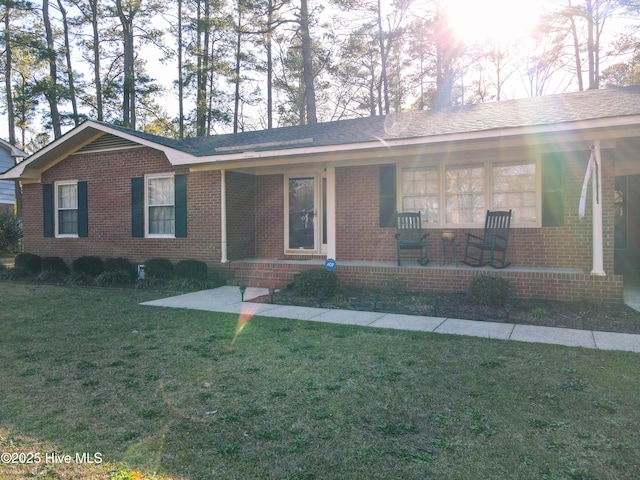 ranch-style home featuring a front lawn, covered porch, and brick siding