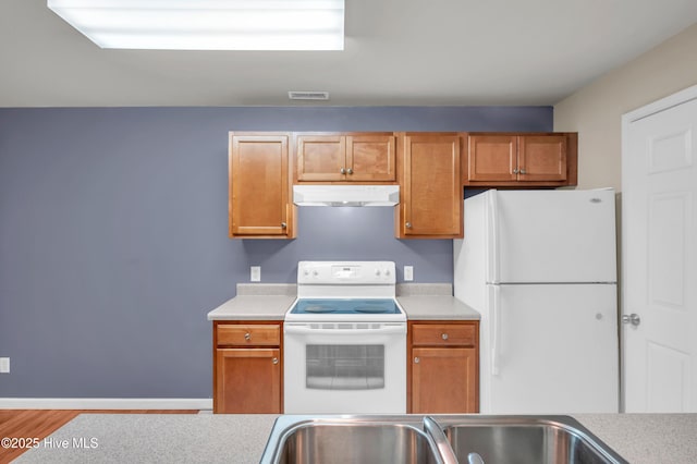 kitchen with under cabinet range hood, visible vents, white appliances, and light countertops