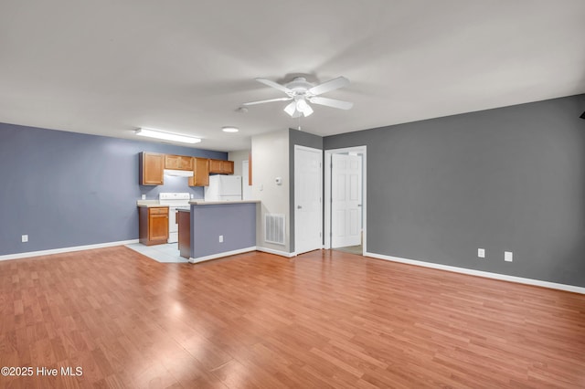 unfurnished living room featuring light wood-type flooring, visible vents, baseboards, and a ceiling fan