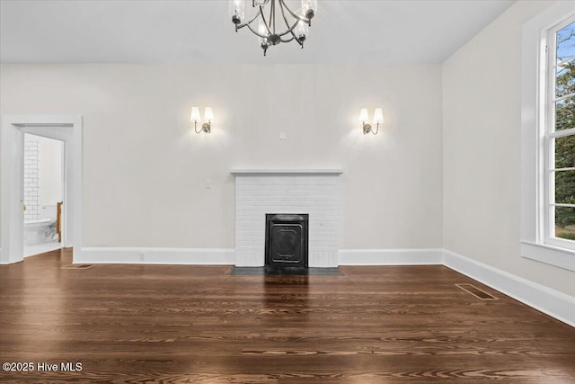 unfurnished living room with visible vents, baseboards, a notable chandelier, and wood finished floors