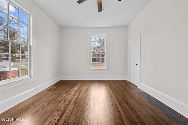 empty room with visible vents, baseboards, dark wood-style floors, and a ceiling fan