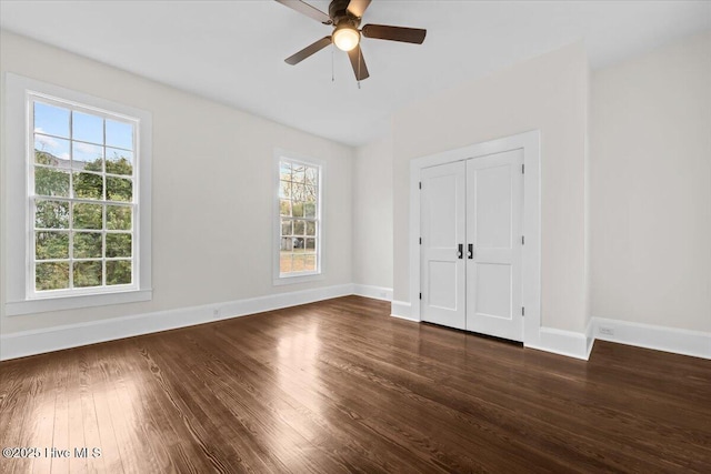 unfurnished bedroom featuring a closet, ceiling fan, dark wood-type flooring, and baseboards