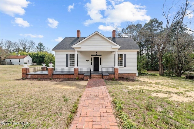 bungalow with a porch, a front lawn, roof with shingles, and a chimney