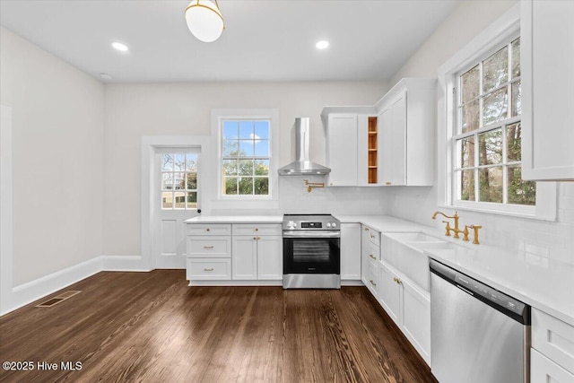 kitchen featuring visible vents, dark wood finished floors, light countertops, appliances with stainless steel finishes, and wall chimney exhaust hood