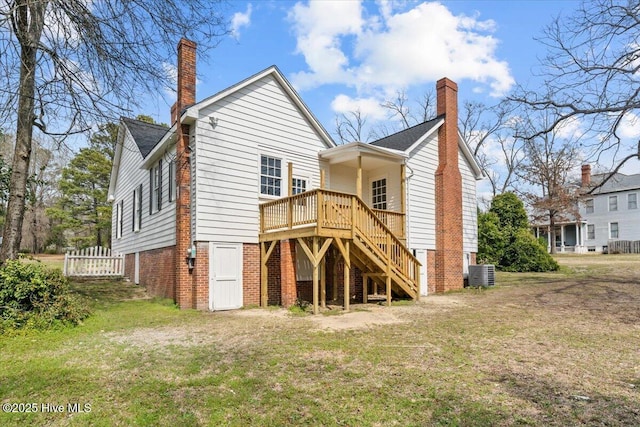 back of house with central air condition unit, stairway, a lawn, and a chimney