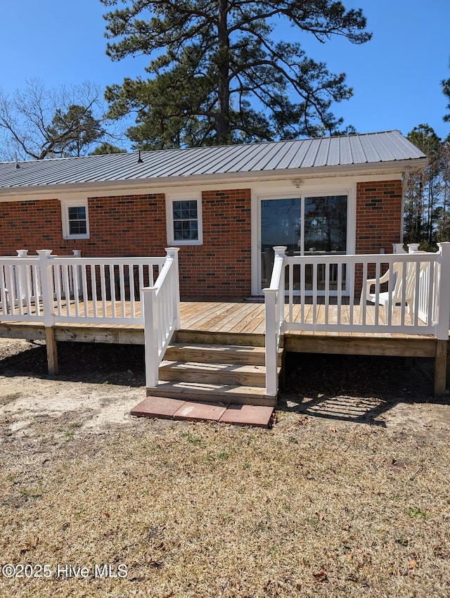 exterior space featuring brick siding, metal roof, and a deck