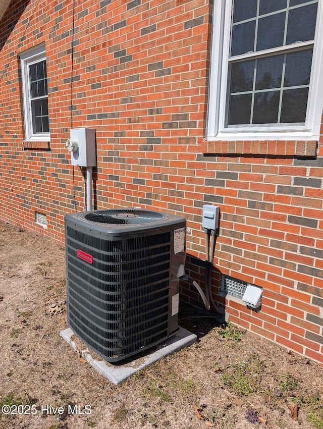 details featuring crawl space, cooling unit, and brick siding