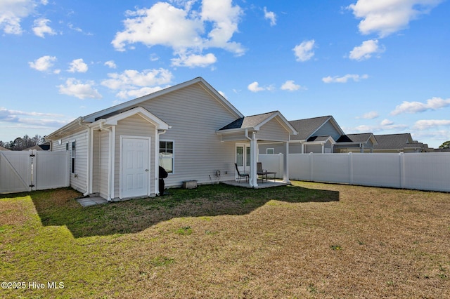 rear view of property featuring an outbuilding, a gate, a fenced backyard, a yard, and a patio area