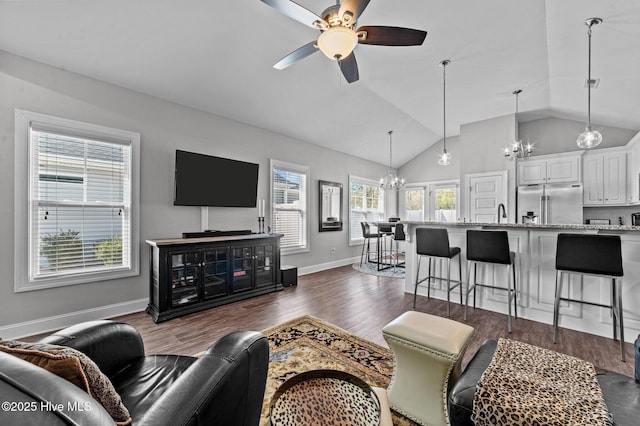 living area with baseboards, lofted ceiling, dark wood-style flooring, and ceiling fan with notable chandelier