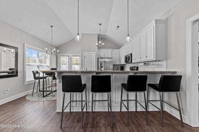 kitchen with a peninsula, stainless steel appliances, an inviting chandelier, white cabinetry, and dark wood-style flooring