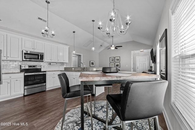 kitchen with visible vents, a peninsula, dark wood-style flooring, stainless steel appliances, and white cabinets