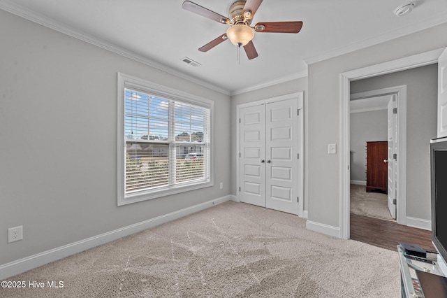 unfurnished bedroom featuring visible vents, ornamental molding, a closet, carpet flooring, and baseboards