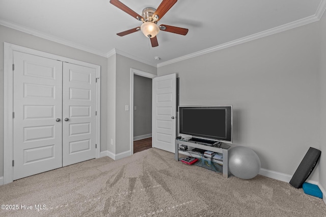 carpeted bedroom with a closet, a ceiling fan, crown molding, and baseboards