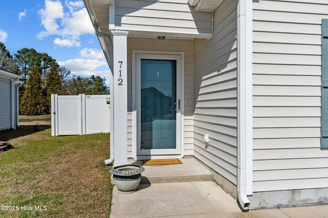 view of exterior entry featuring a yard and fence