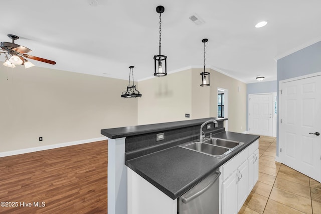 kitchen featuring dark countertops, visible vents, dishwasher, and a sink