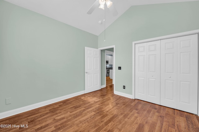 unfurnished bedroom with high vaulted ceiling, a ceiling fan, wood finished floors, a closet, and baseboards