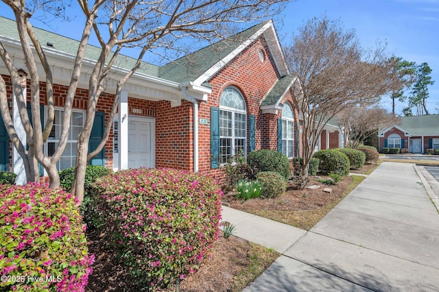 view of side of home featuring brick siding and a shingled roof