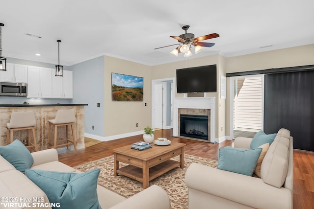 living area featuring baseboards, a ceiling fan, and light wood-style floors