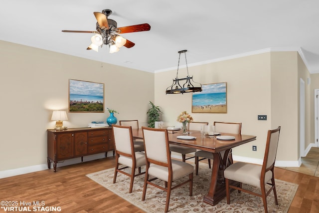 dining space with baseboards, crown molding, ceiling fan, and wood finished floors