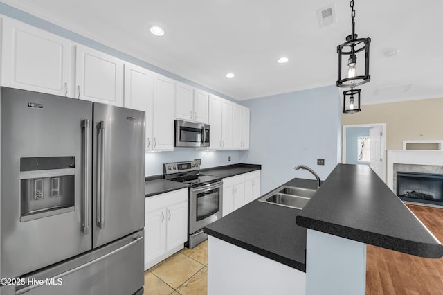 kitchen featuring white cabinetry, dark countertops, appliances with stainless steel finishes, and a sink