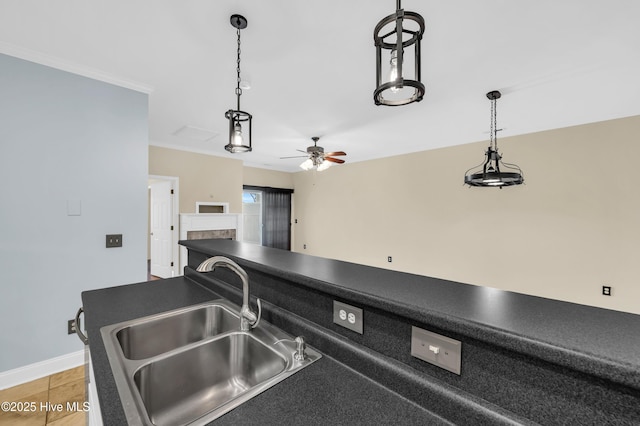 kitchen with dark countertops, decorative light fixtures, a ceiling fan, and a sink