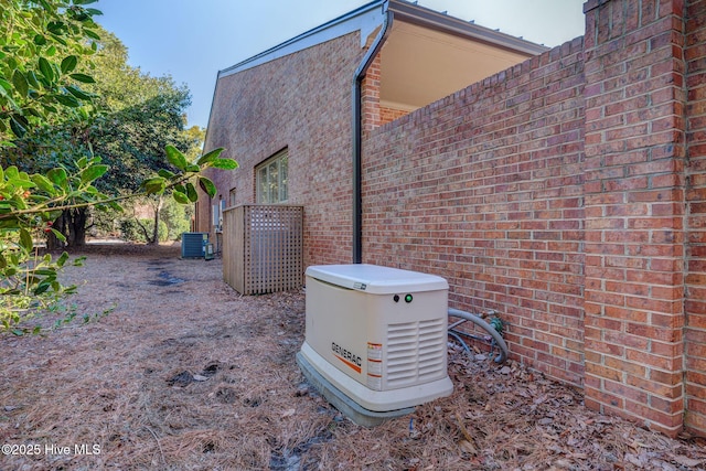 details featuring a power unit, brick siding, and central AC unit