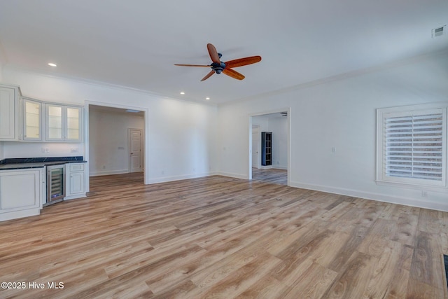 unfurnished living room with ornamental molding, beverage cooler, light wood-type flooring, and ceiling fan