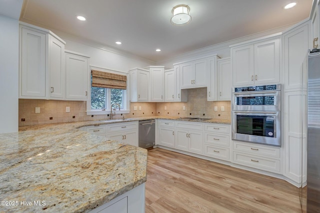 kitchen with light stone counters, a sink, appliances with stainless steel finishes, light wood-type flooring, and backsplash