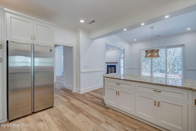 kitchen with light stone counters, visible vents, light wood finished floors, built in fridge, and white cabinetry