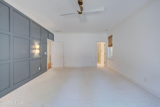 interior space featuring baseboards, ceiling fan, crown molding, and a decorative wall