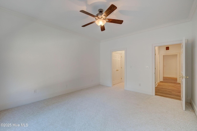 carpeted spare room featuring baseboards, crown molding, and a ceiling fan