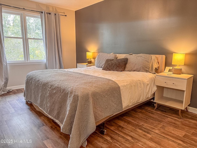 bedroom with baseboards and wood finished floors