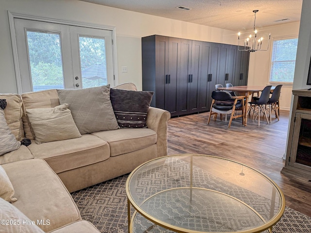 living area featuring visible vents, a notable chandelier, and wood finished floors