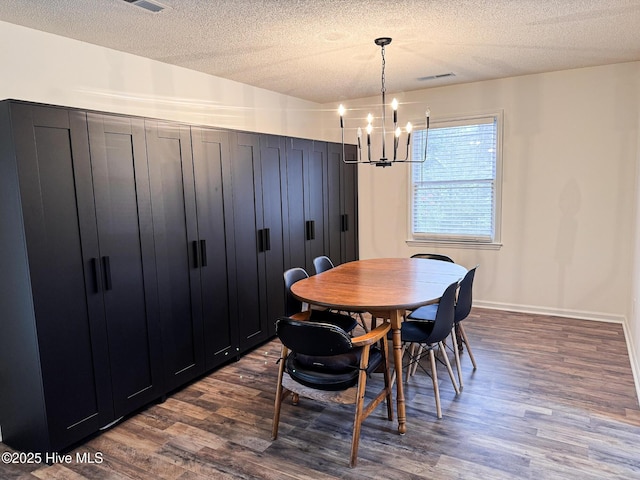 dining room featuring a chandelier, dark wood finished floors, a textured ceiling, and baseboards