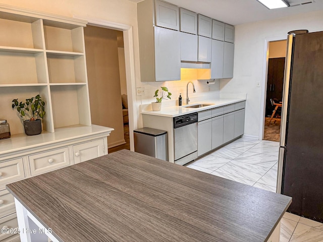 kitchen featuring marble finish floor, gray cabinetry, a sink, stainless steel appliances, and decorative backsplash