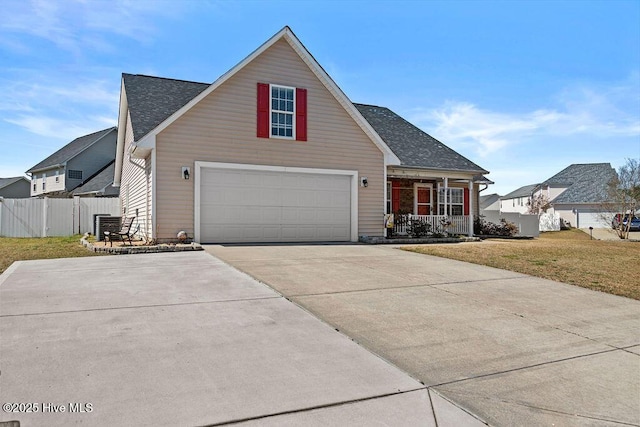 traditional-style home with fence, roof with shingles, a front yard, covered porch, and driveway