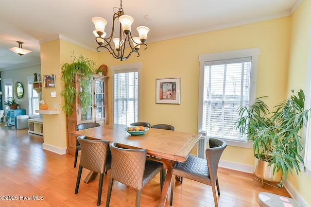 dining space featuring a notable chandelier, plenty of natural light, baseboards, and light wood finished floors