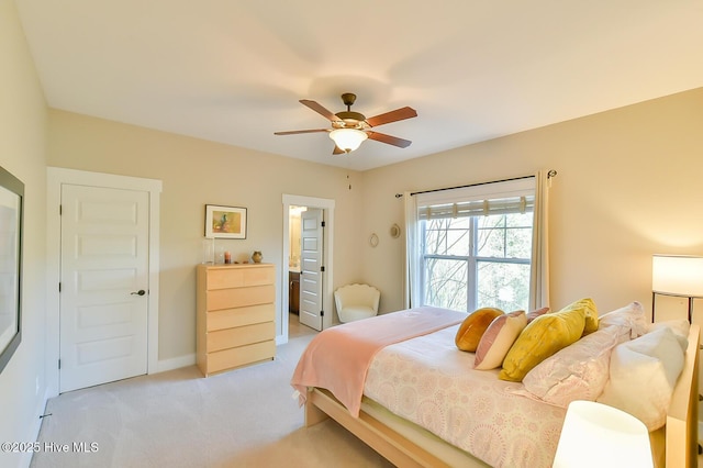 bedroom featuring connected bathroom, light carpet, baseboards, and a ceiling fan