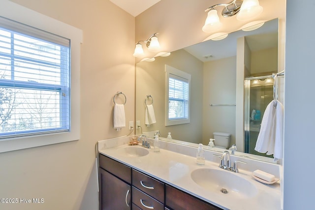 full bath featuring a sink, an enclosed shower, toilet, and double vanity