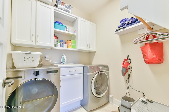 clothes washing area with washer and dryer and cabinet space