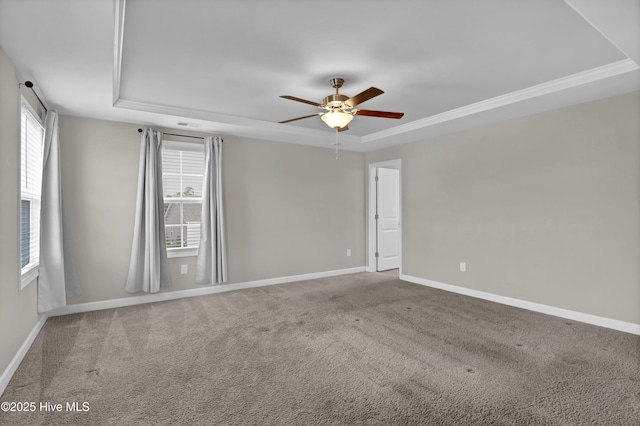 carpeted spare room with a raised ceiling, baseboards, and ceiling fan