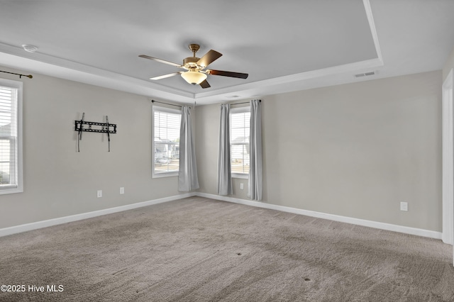 unfurnished room with visible vents, ceiling fan, baseboards, and a tray ceiling